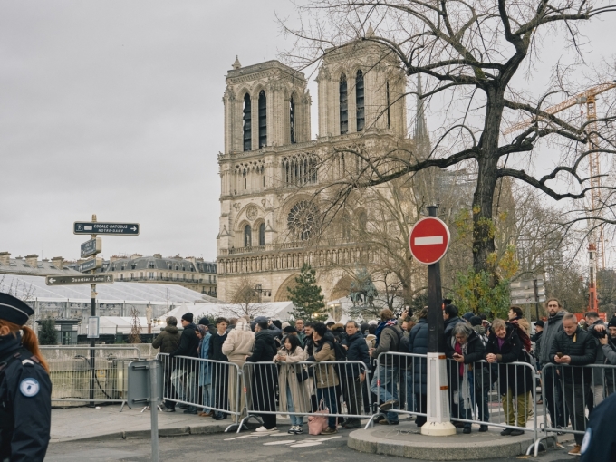 Người dân, du khách đứng ngoài hàng rào trong ngày nhà thờ Đức Bà Paris mở cửa lại hôm 7/12. Ảnh: AFP