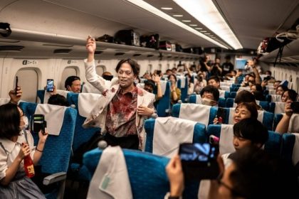 Hành khách chụp ảnh cùng diễn viên đóng xác sống trên tàu từ Tokyo tới Osaka hôm 19/10. Ảnh: AFP